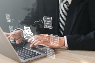 © Pakin - stock.adobe.com Foto: Mann vor Laptop mit schwebendem digitalen Brief über der Tastatur